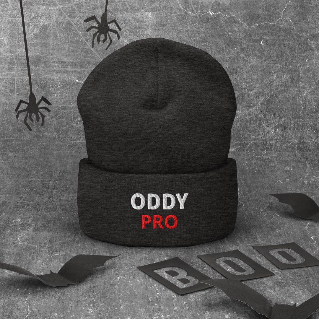Oddy Pro Cuffed Beanie in black, featuring embroidered text, set against a spooky gray background.